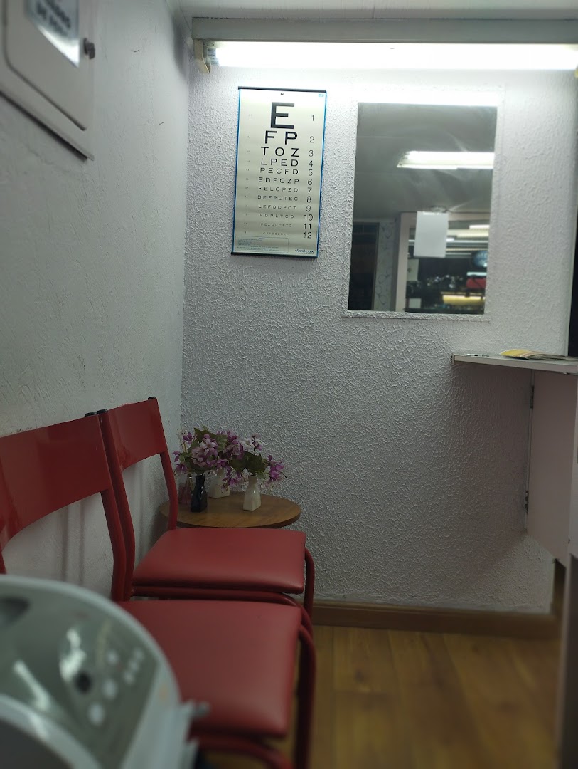An eye chart and red chairs in a waiting area, possibly for an optician.