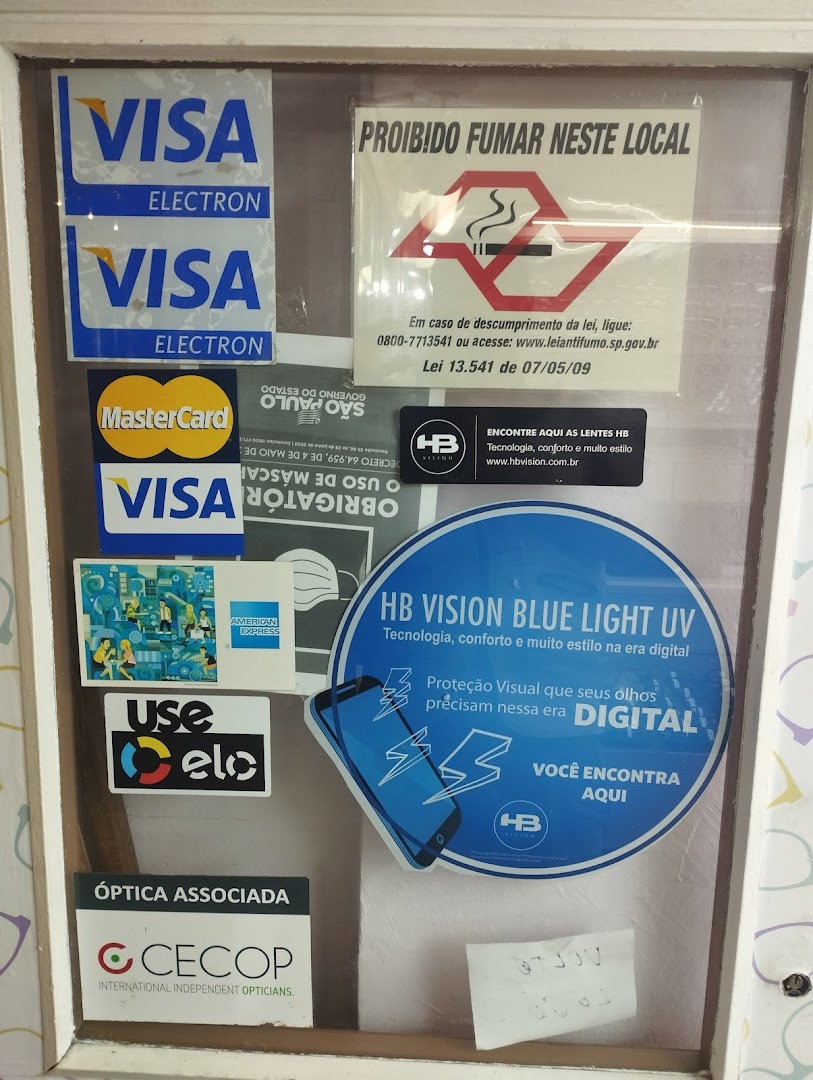 A shop window displaying various payment method logos, a no-smoking sign, and optical product advertisements.