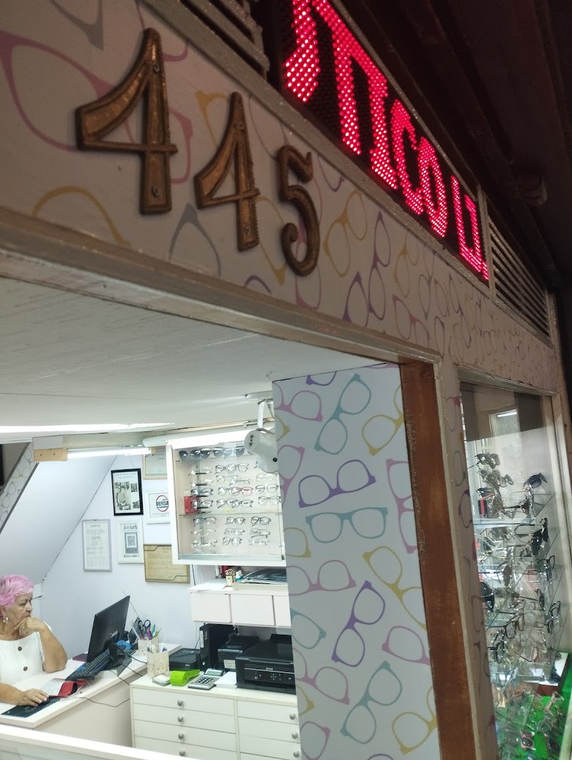 The entrance of an optical shop with the number 445 and the shop name illuminated in red.