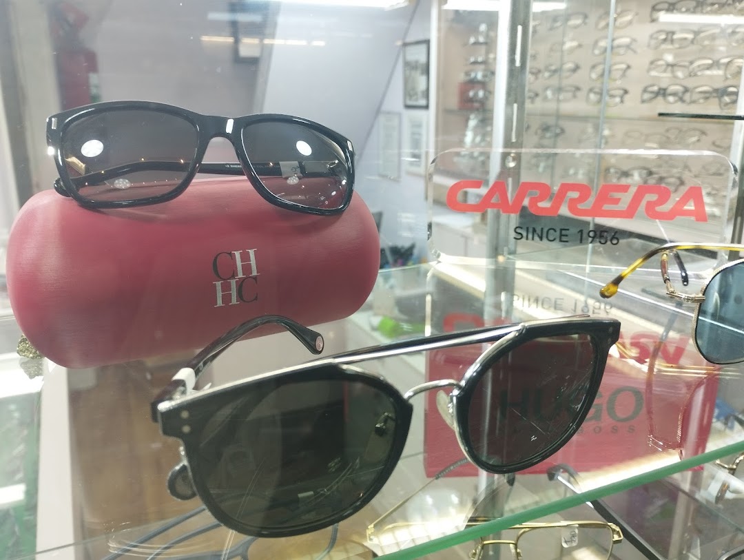 A display of stylish sunglasses, including Carrera and Hugo Boss brands, in a retail store.