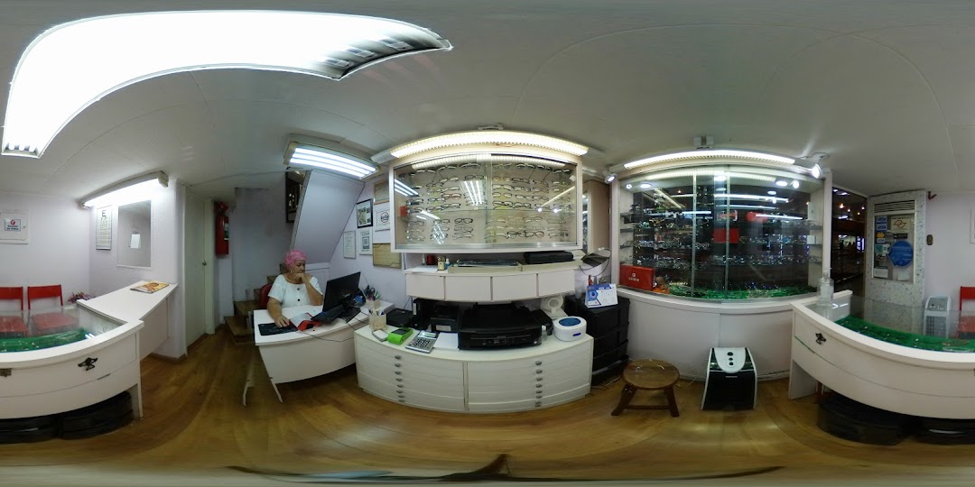 Interior of an optical shop with a woman at a desk and displays of eyeglasses.
