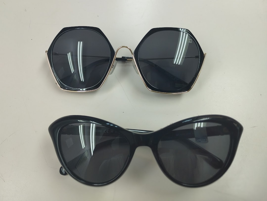 Two pairs of stylish black sunglasses, one hexagonal and one cat-eye, displayed on a white surface.