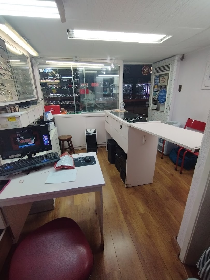 Interior view of an optical shop with displays of eyeglasses and a workstation.
