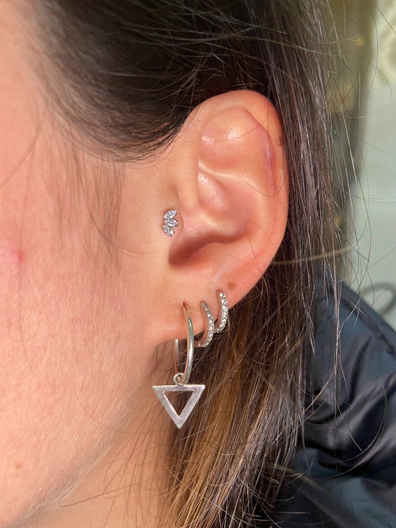Close-up of a person's ear with multiple piercings and stylish jewelry.