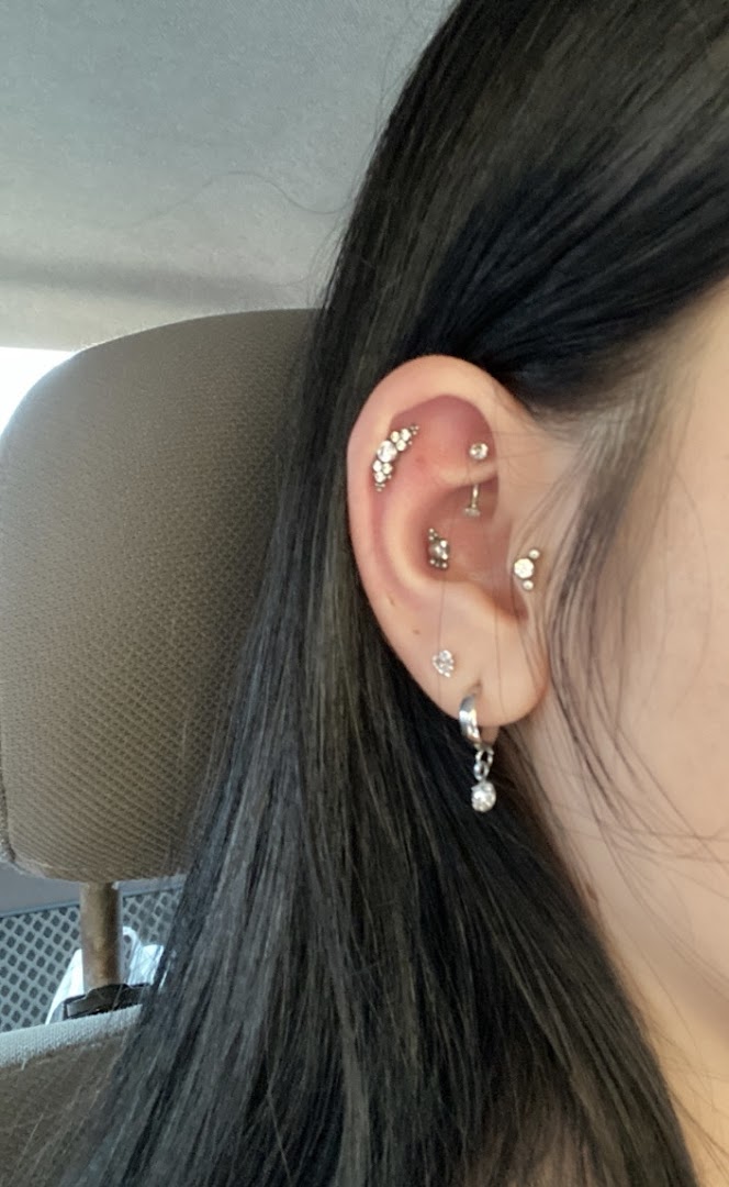 A close-up of a person's ear adorned with multiple stylish piercings and jewelry.