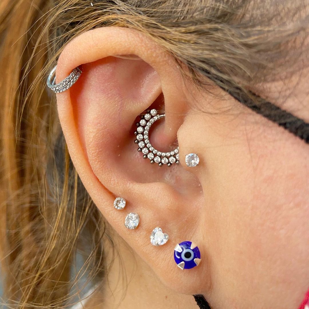 A close-up of a person's ear showcasing multiple stylish piercings and jewelry.