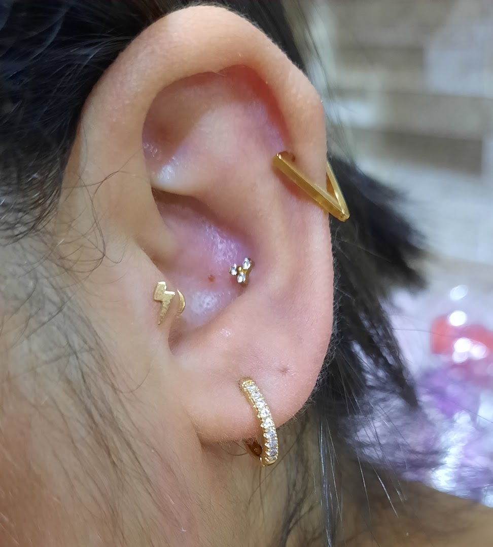 Close-up of a person's ear with multiple stylish gold piercings and jewelry.