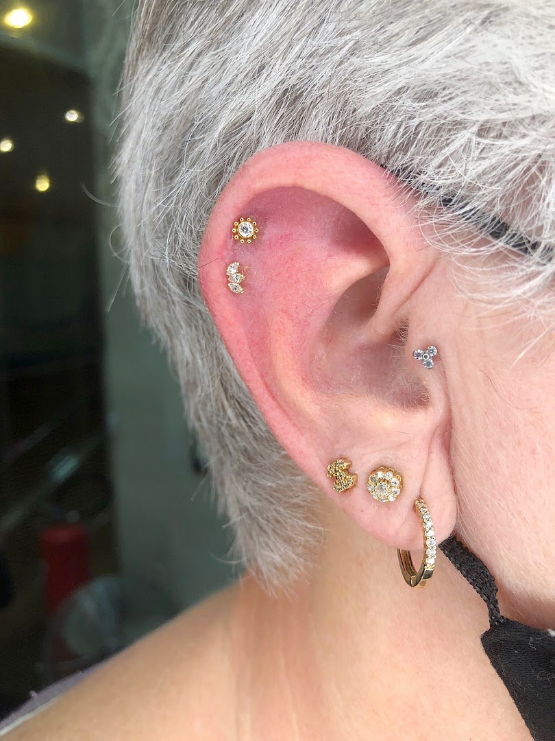 A close-up of a person's ear adorned with multiple stylish piercings and jewelry.