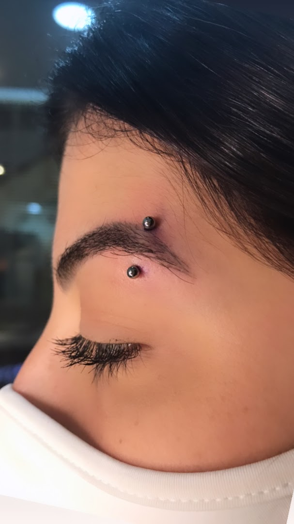 Close-up of a person's eyebrow with two silver piercings.