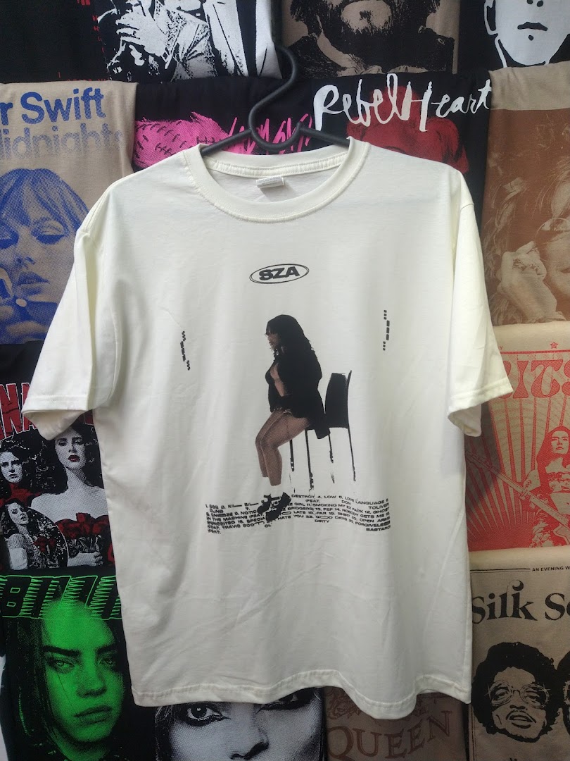 A cream-colored t-shirt with a graphic print of a woman sitting on a chair and text.