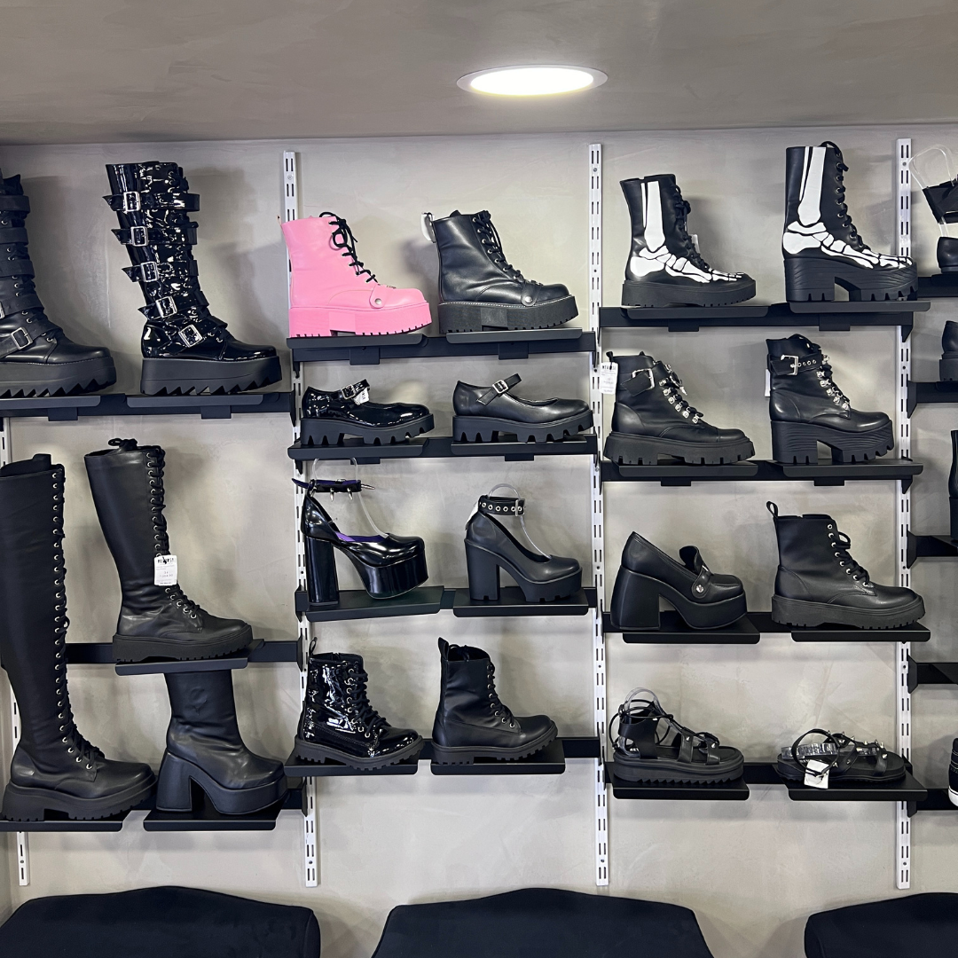 A wall display showcasing a variety of platform boots, heels, and shoes in black and pink.