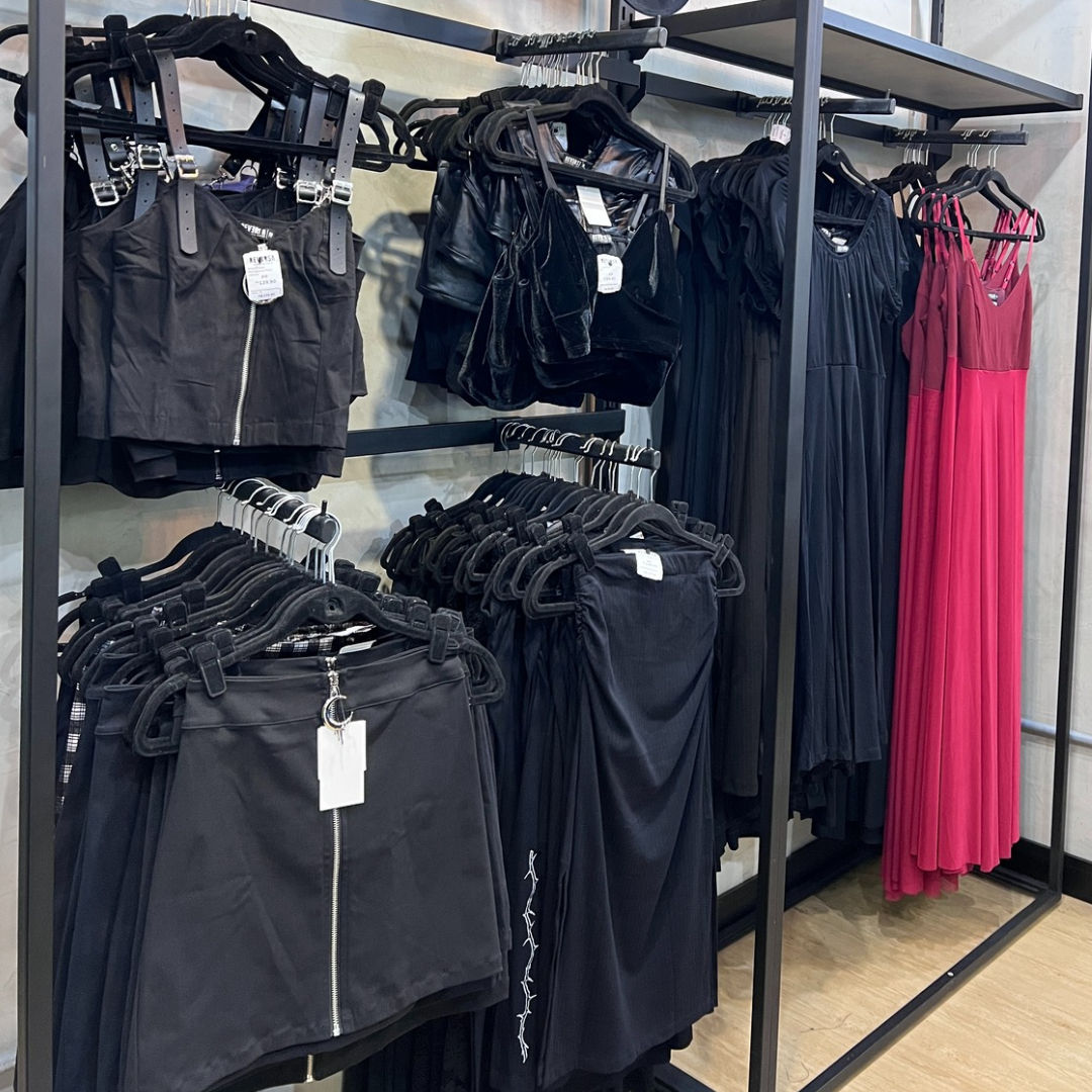 A display of trendy black and pink clothing items on hangers in a retail store.