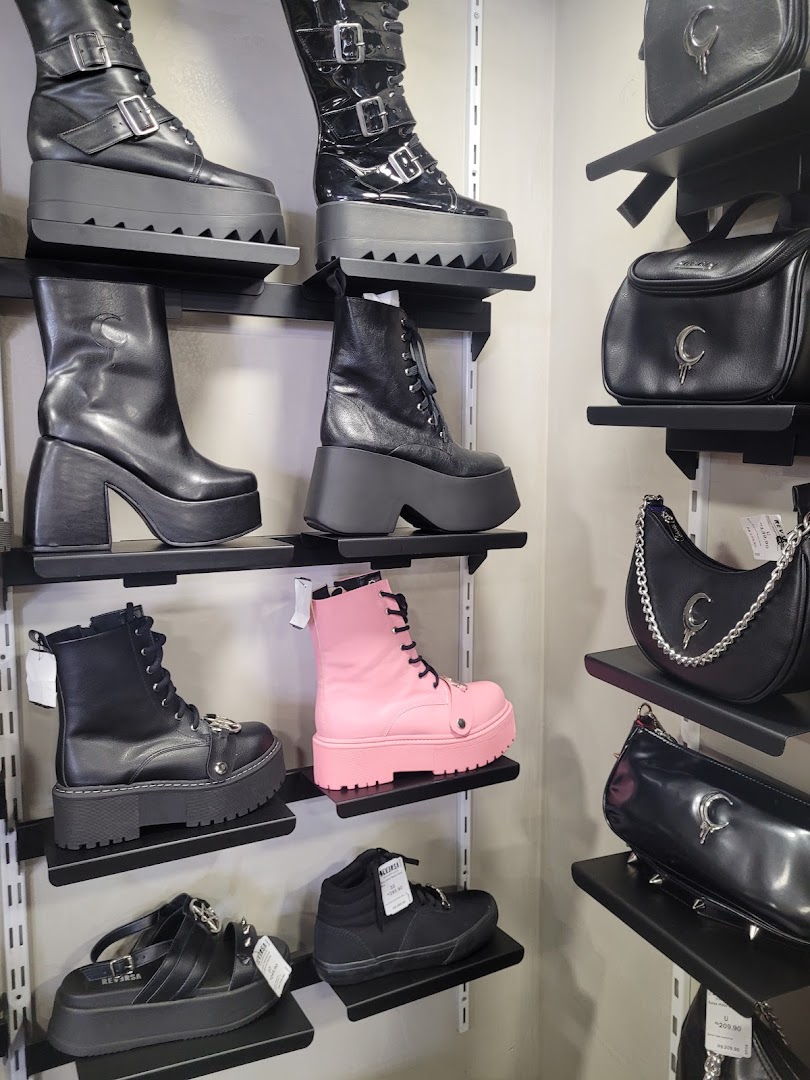 A display of gothic-style platform boots and handbags on shelves.