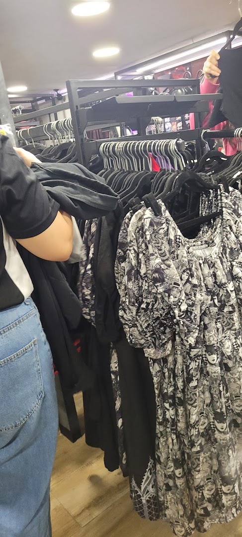 A person browsing through racks of clothing, featuring a dress with a unique graphic print.