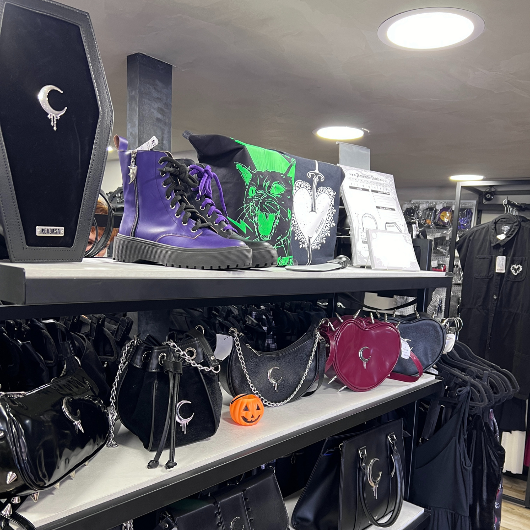 A display of gothic-style fashion accessories including boots, handbags, and clothing.