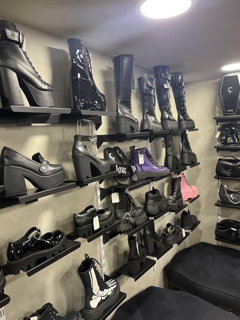 A display of various gothic and platform shoes, including boots and heels, on shelves.