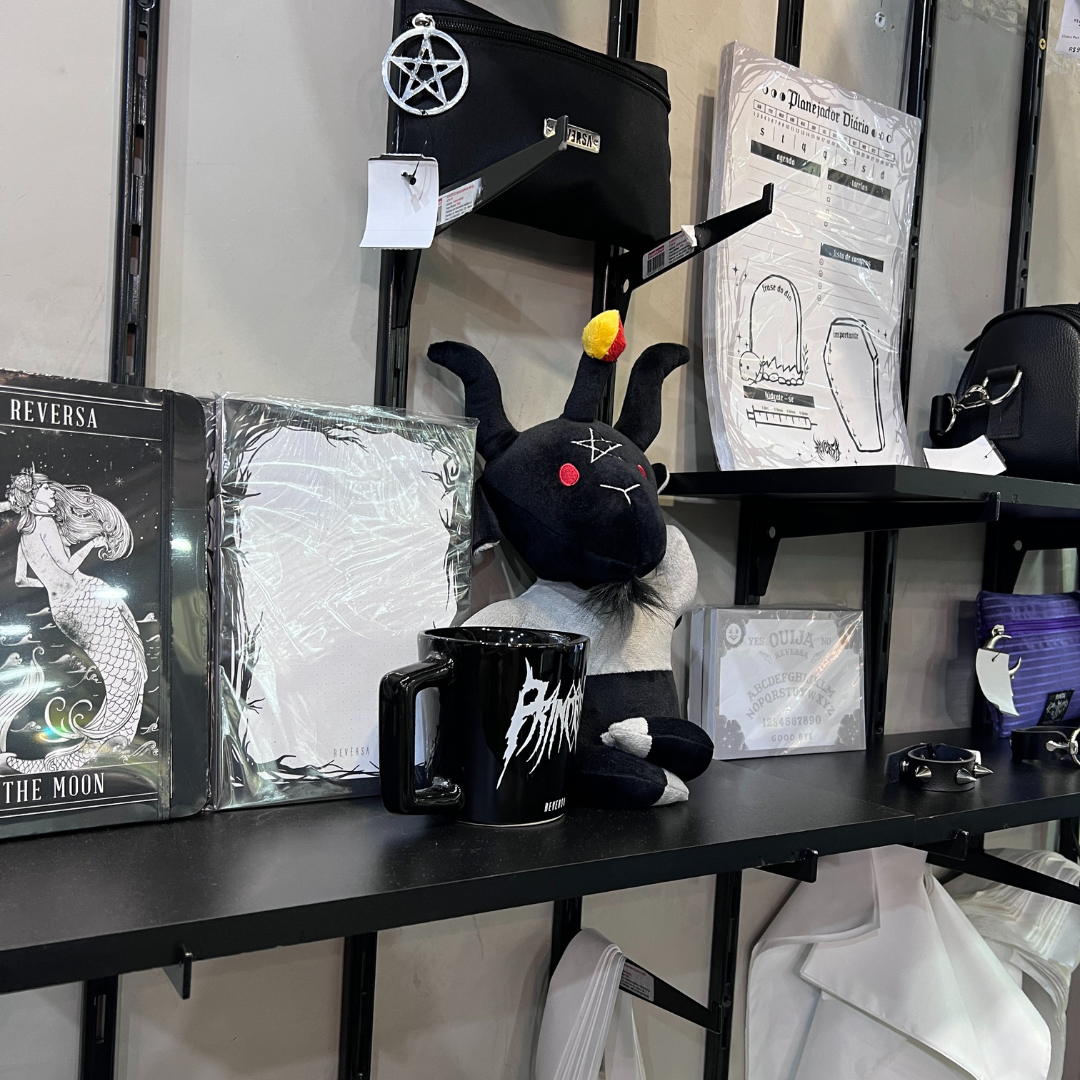A shelf displays various gothic-themed merchandise, including a plush toy, mug, and planner.
