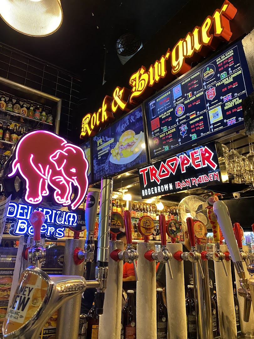 A bar counter with multiple beer taps and neon signs, including a pink elephant and the shop's name.