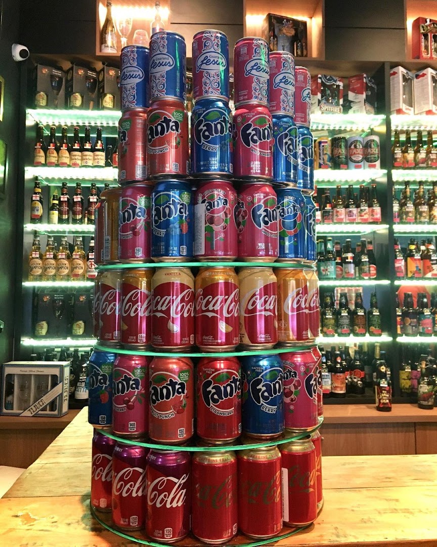 A pyramid display of various soda cans, including Coca-Cola, Fanta, and Jesus, in a retail setting.