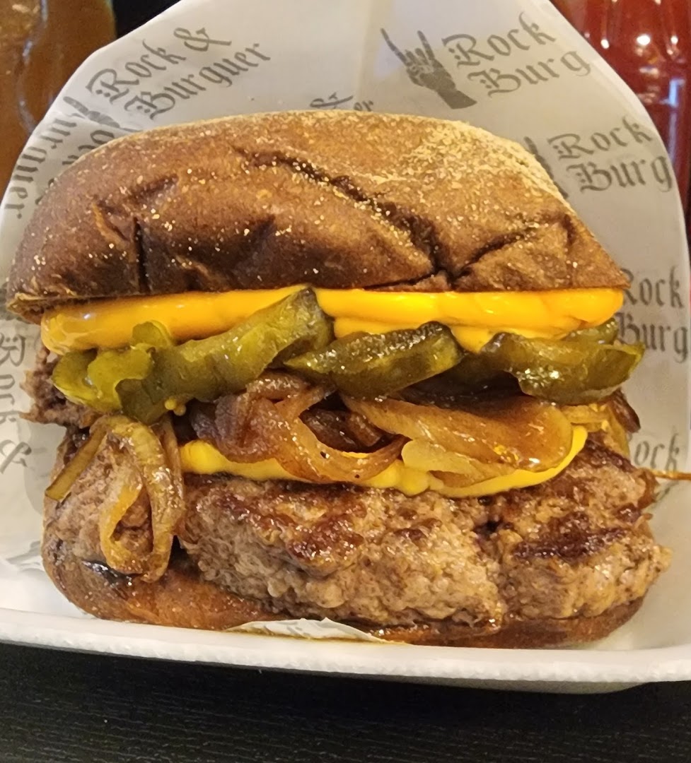 A close-up shot of a delicious burger with cheese, pickles, and caramelized onions.
