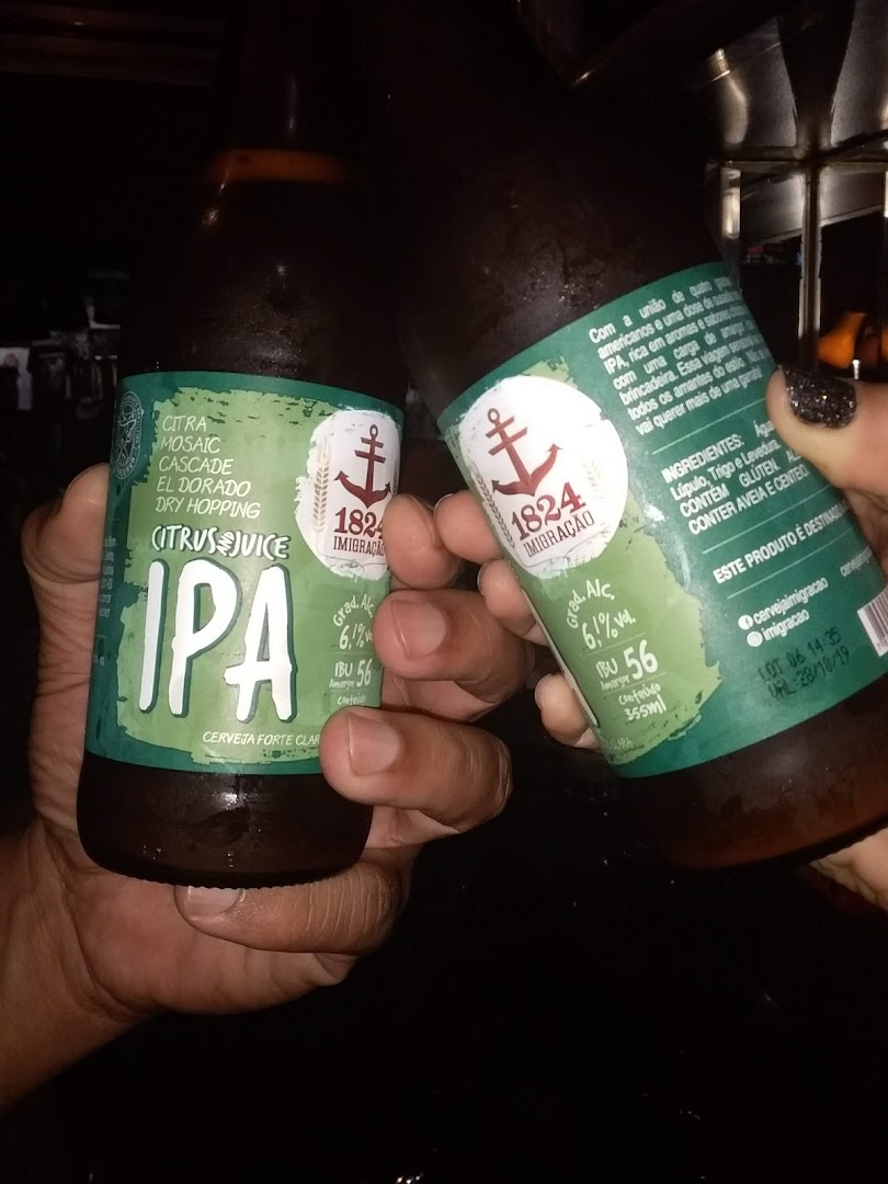 Two hands holding bottles of IPA beer with green labels.