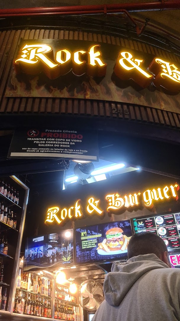 A person looks at a brightly lit burger joint with a large illuminated sign.