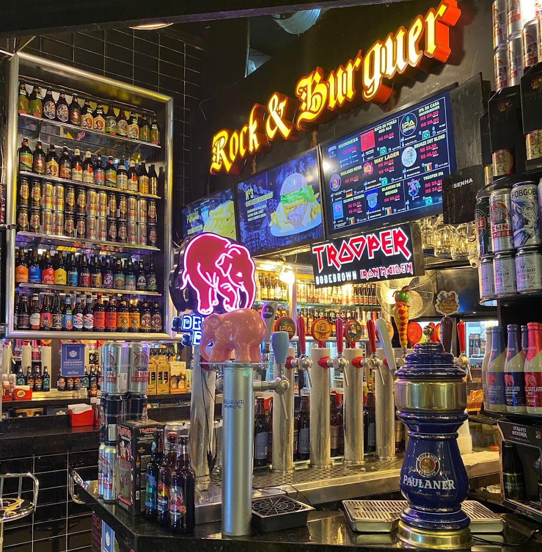 A bar counter with beer taps, shelves of beer bottles, and digital menus displaying drinks and food.