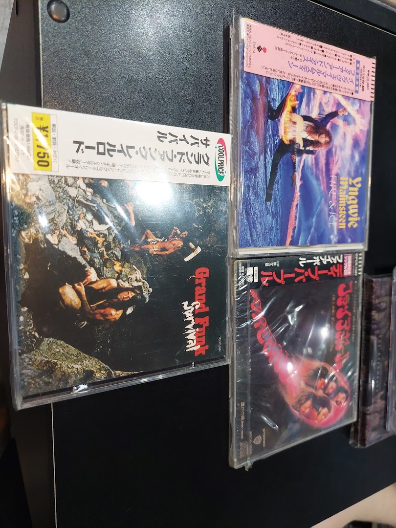 Several music CDs are displayed on a dark surface, featuring album art and Japanese text.
