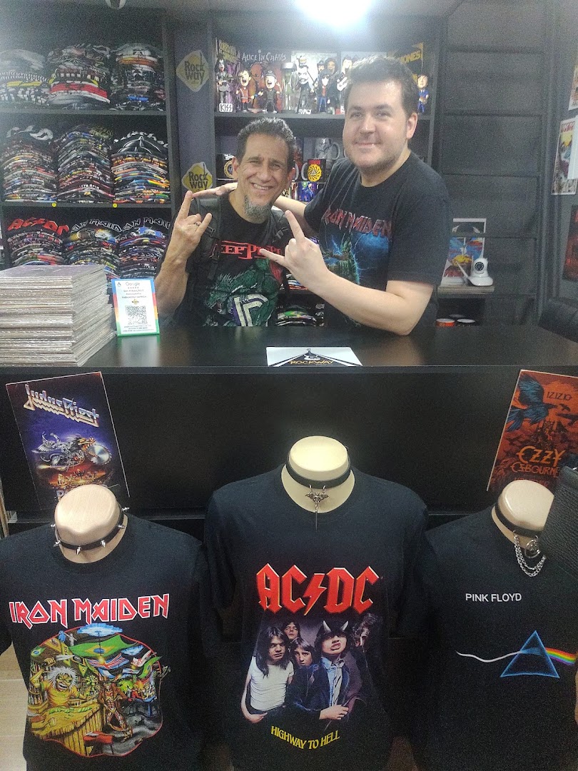 Two men posing in a store filled with band t-shirts and merchandise.