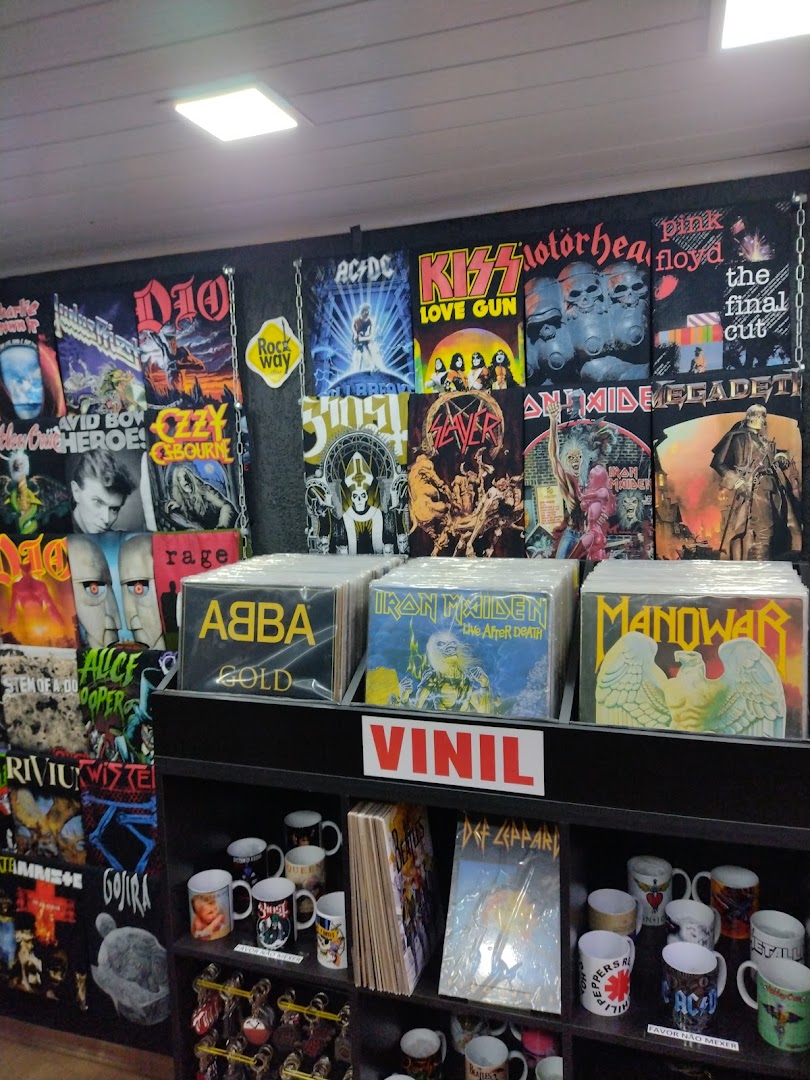 A retail store display featuring band t-shirts, vinyl records, and mugs with rock music themes.