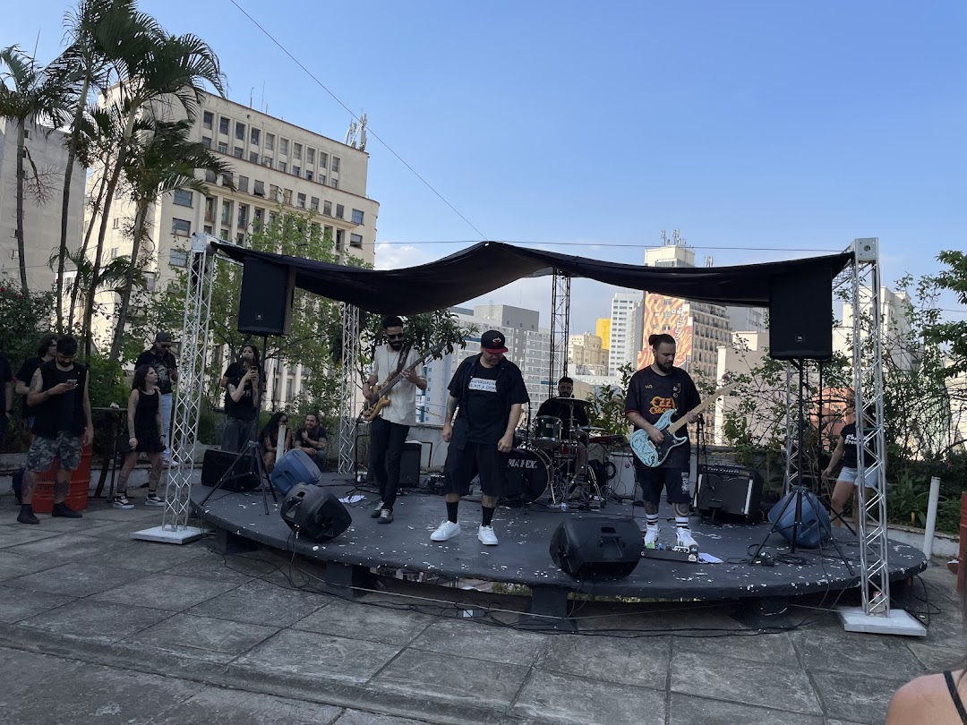 A band performs on an outdoor stage with a city skyline in the background.