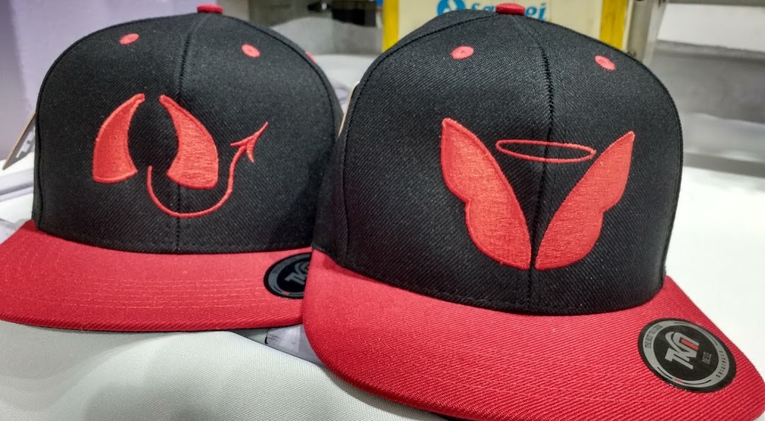 Two black and red baseball caps with embroidered devil and angel designs.