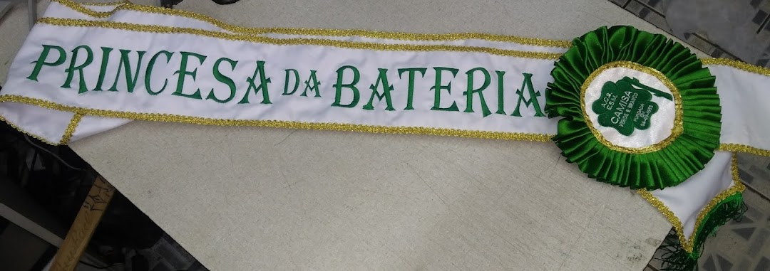 A white sash with green lettering and gold trim, featuring a green rosette.