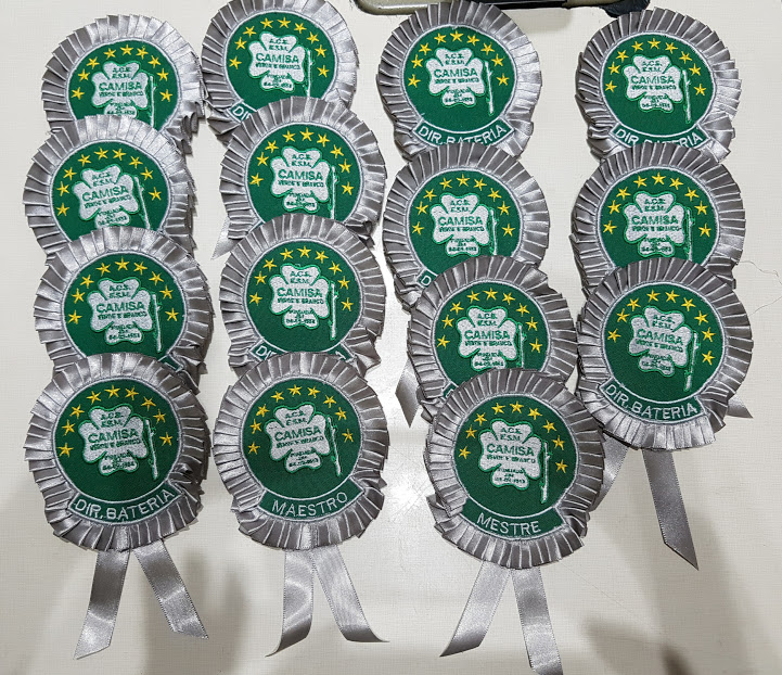 A collection of green and silver rosettes with embroidered text and a cloverleaf emblem.