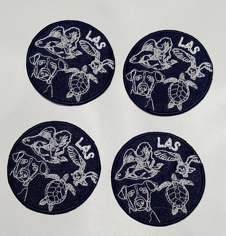 Four circular embroidered patches featuring a dog, sea creatures, and birds with the text 'LAS'.