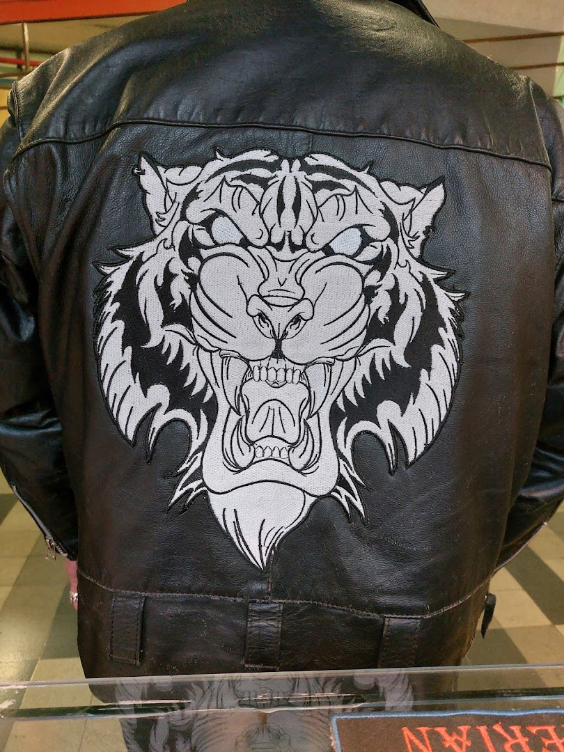 A black leather jacket with a large embroidered tiger face patch on the back.