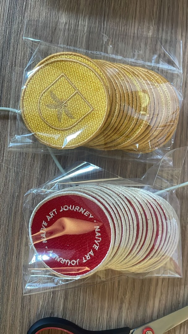 Two stacks of round embroidered patches, one gold with a crest, the other red with text and an image.