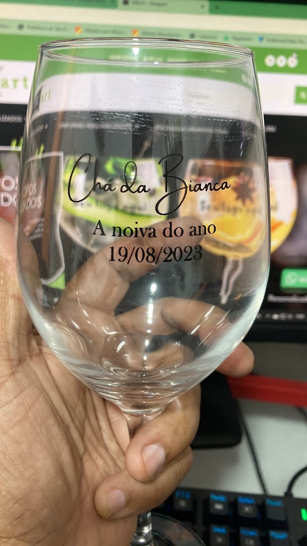 A hand holds a personalized wine glass with custom text and a date.