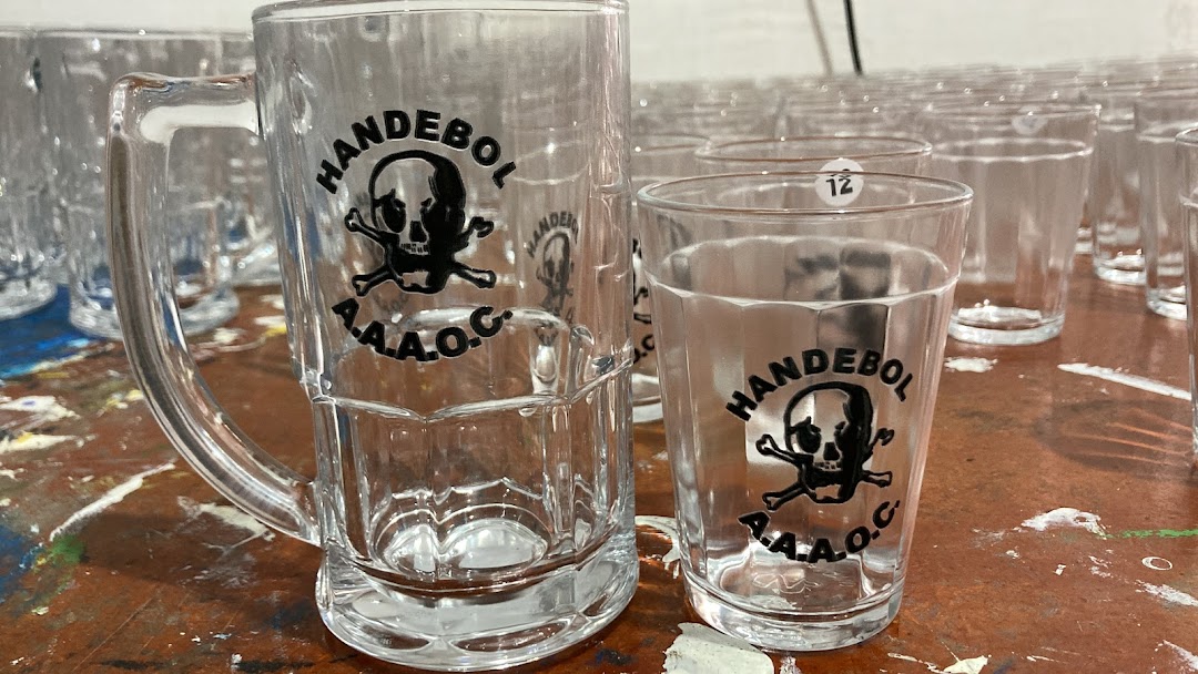 Close-up of personalized glass mugs and shot glasses with a skull logo.