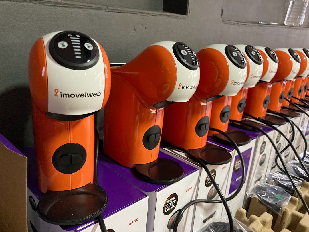A row of orange and white coffee machines are displayed on top of their boxes.
