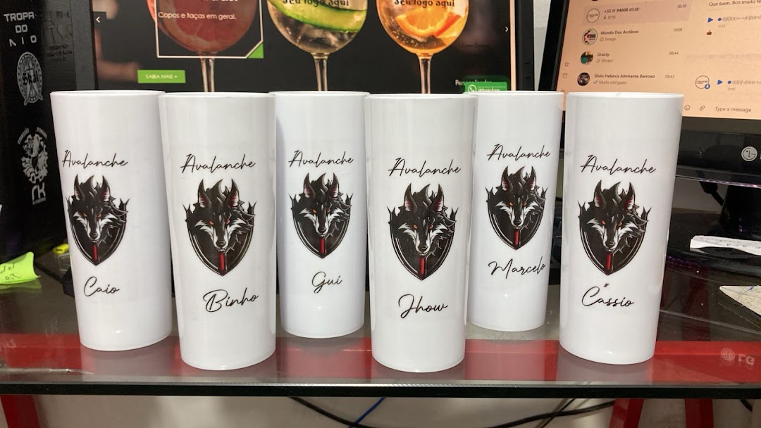 Personalized white tumblers with wolf logos and names displayed on a glass surface.