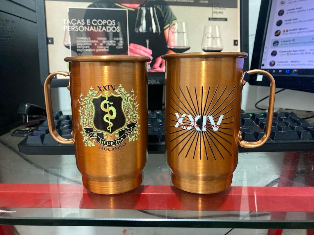 Two personalized copper mugs, one with a medical emblem and the other with a sunburst design.
