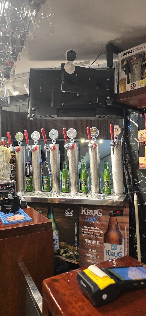 A bar counter with multiple beer taps, bottles, and promotional materials.