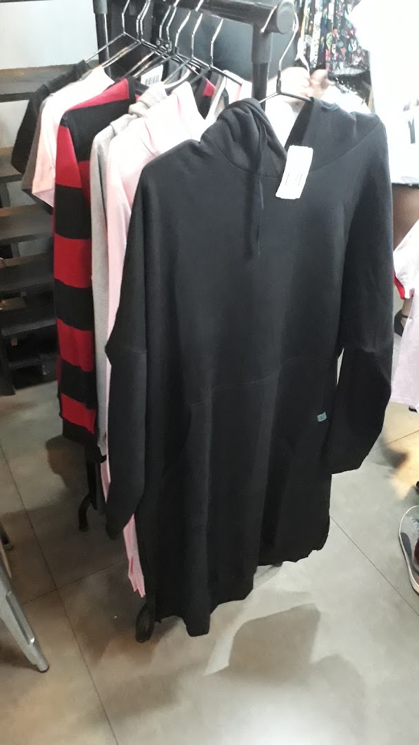 A rack of clothing, featuring a black hoodie dress and other casual wear.