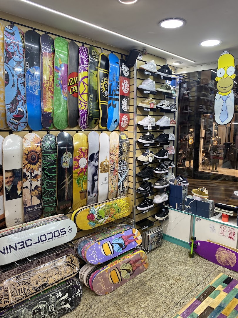 A retail shop interior displaying a wide variety of skateboards and sneakers, with a Homer Simpson cutout.