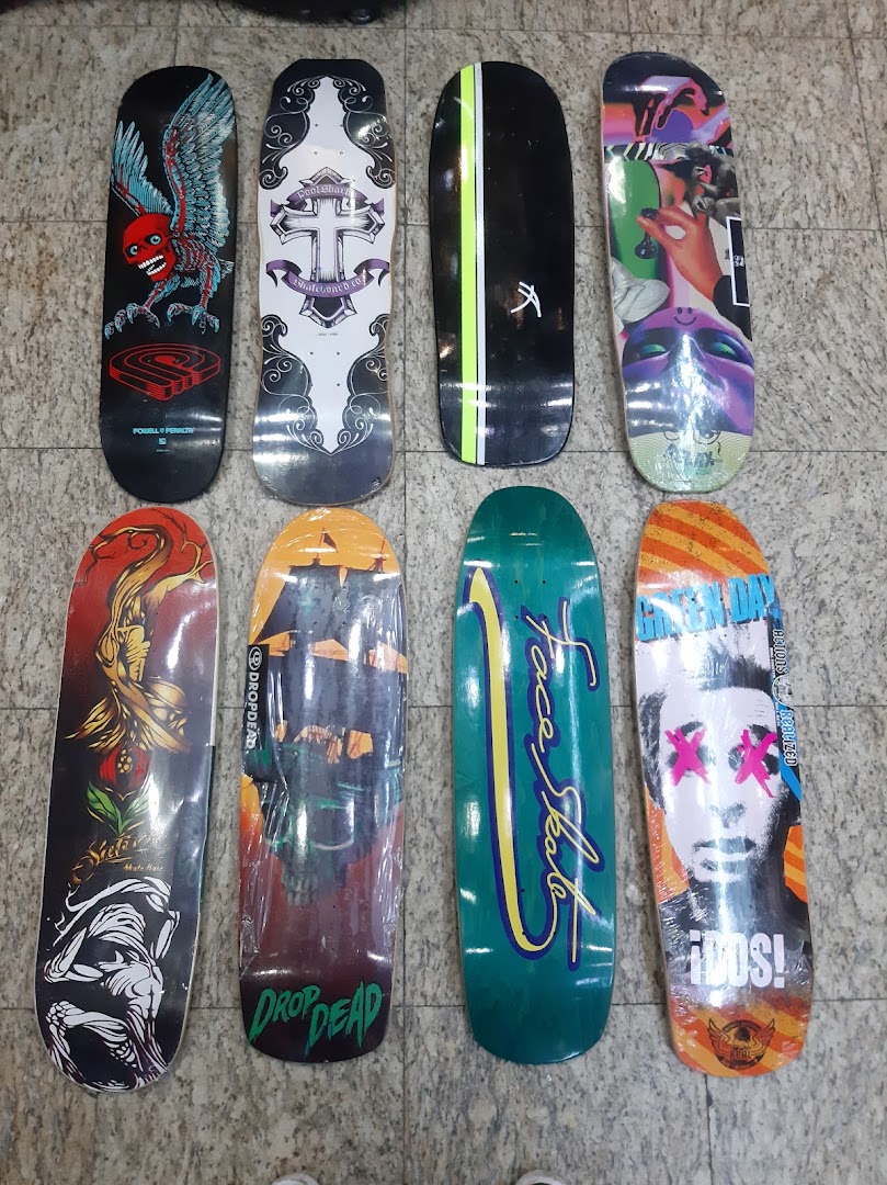 A collection of eight vibrantly designed skateboards laid out on a textured floor.