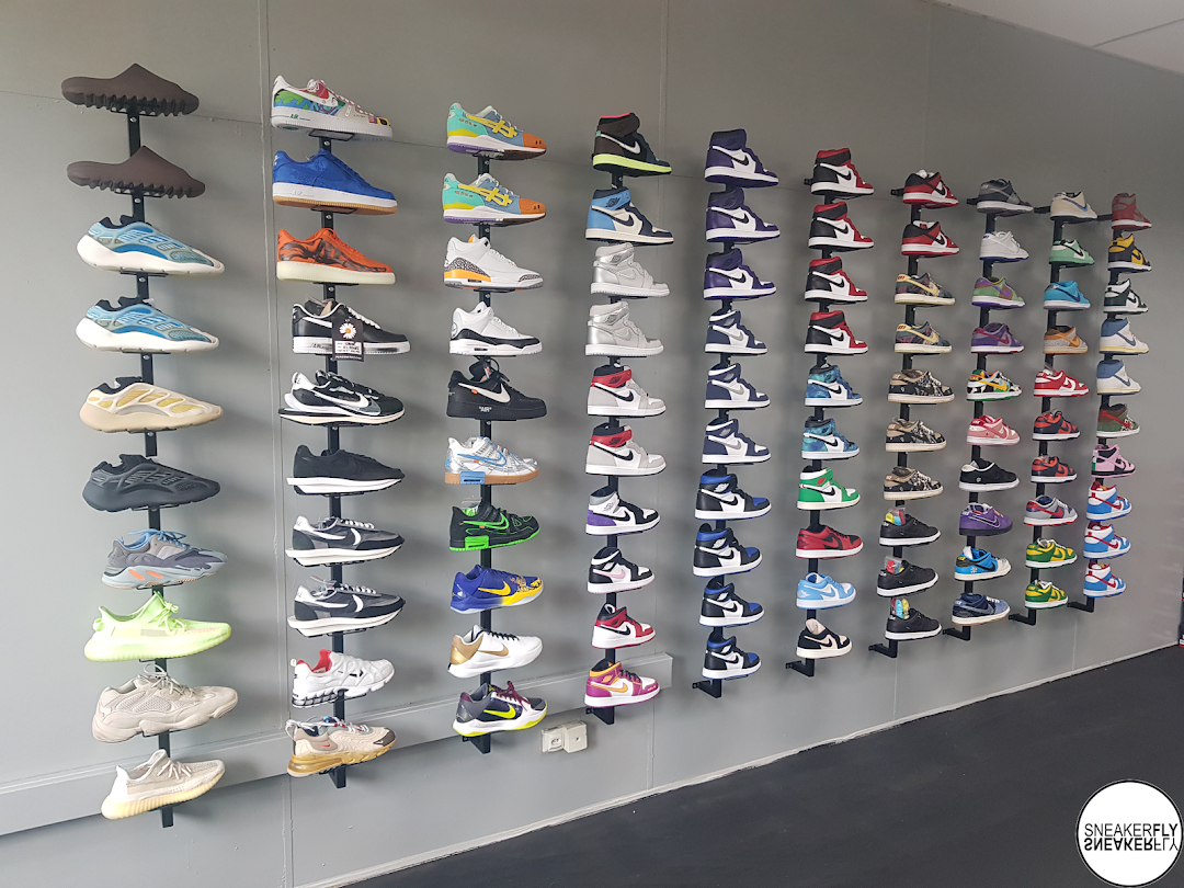 A wall display showcasing a wide variety of sneakers from the shop SNEAKERFLY.