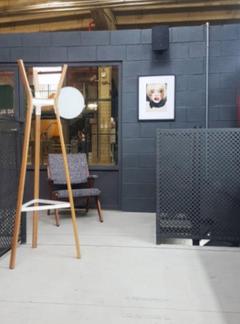 A modern interior space with a unique coat rack, armchair, and artwork.