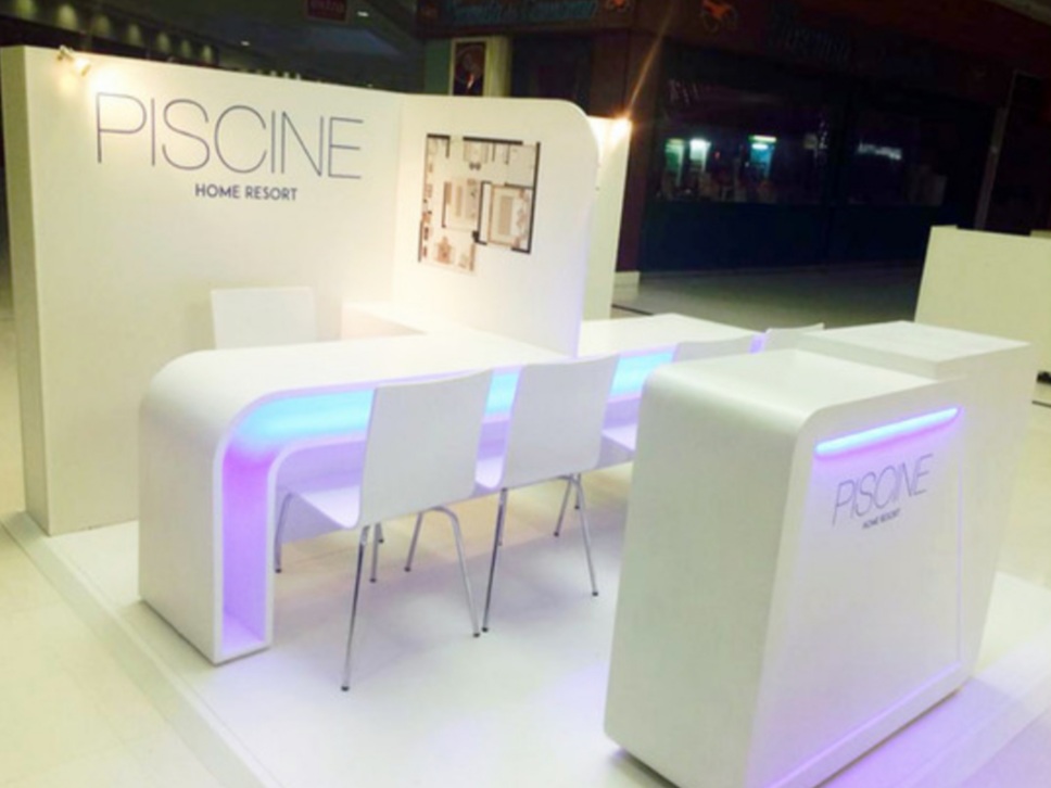 A modern white reception desk and seating area with ambient lighting.