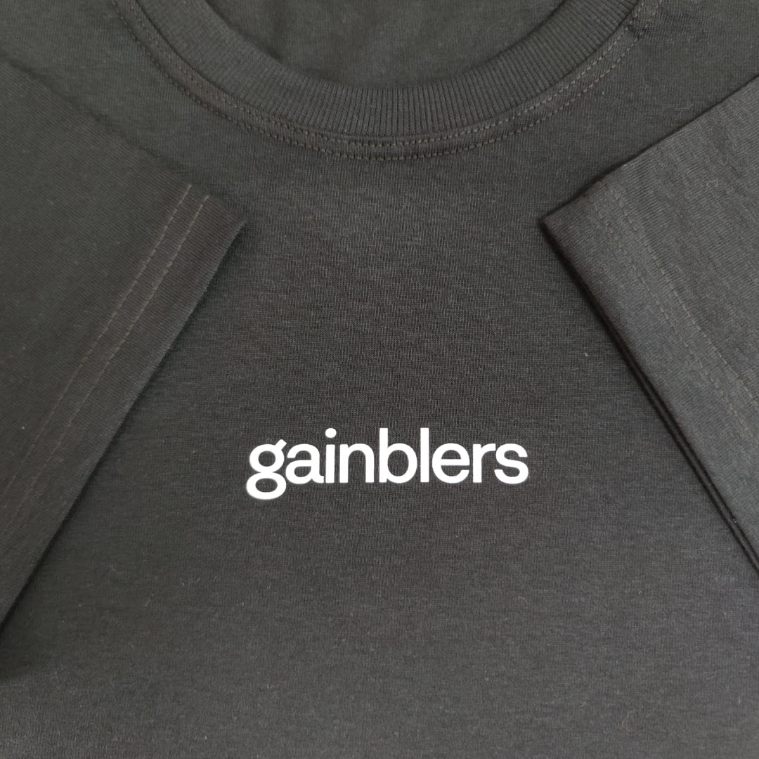 Close-up of a black t-shirt with the white text 'gainblers' printed on it.